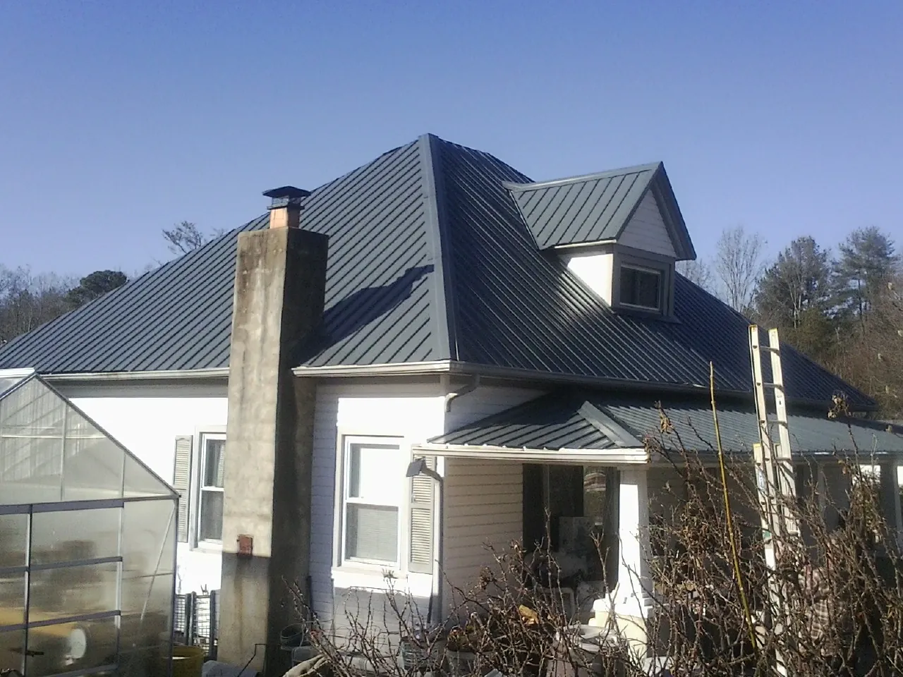 Dark blue standing seam metal roof on a white farmhouse with dormer — Slate & Tile Roof Repair by Roofing Brothers in Elverta