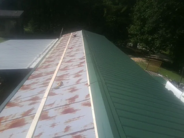 Old rusted panels beside newly installed green metal roofing — Wind Damage Roof Repair by Roofing Brothers in Elverta
