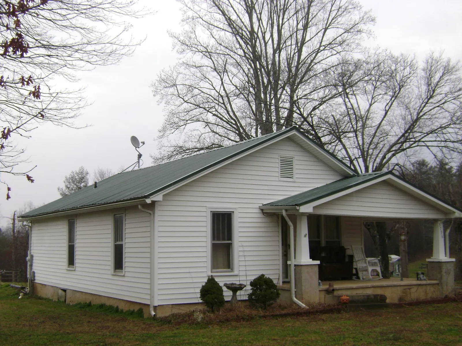 Green metal roof on a white bungalow with a side porch in Elverta