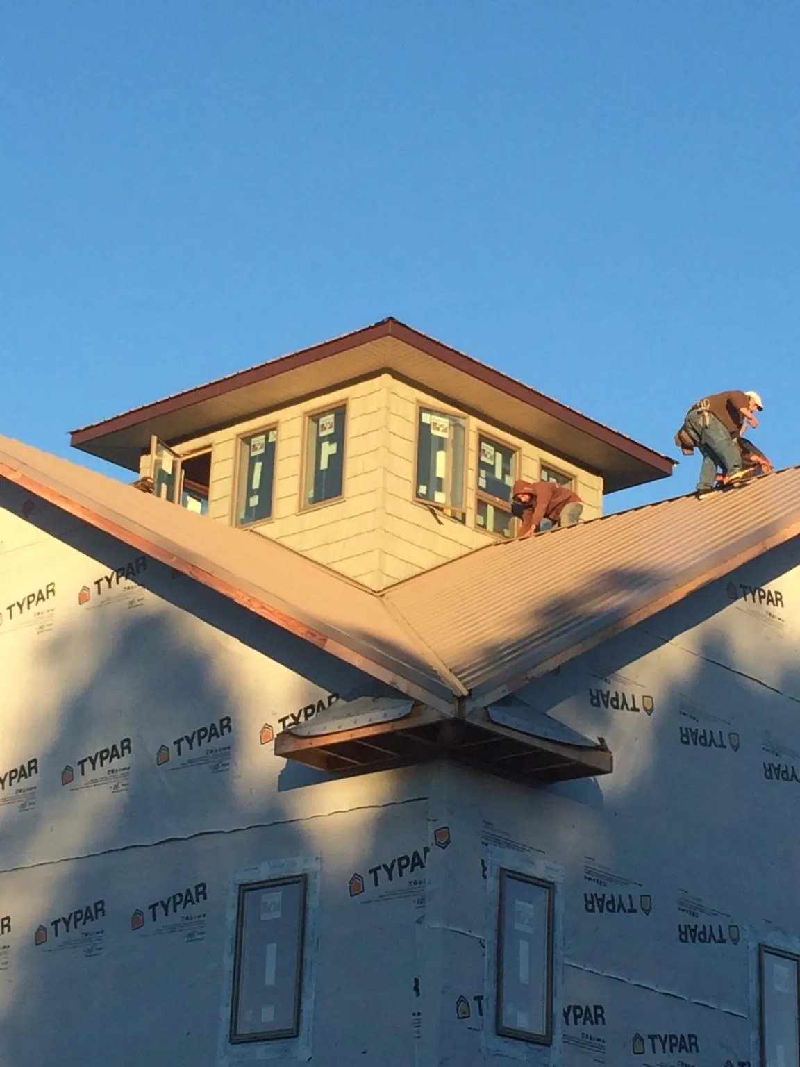 Roofers working around a rooftop cupola on a new metal roof at sunset — Roof Waterproofing in Elverta by Roofing Brothers